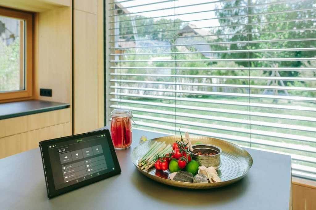 A smart home dashboard on a tablet controlling lights, temperature, and window blinds.